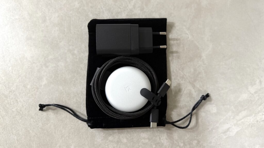 여행용 파우치 위에 놓인 ButterFly 본체와 전원 어댑터, USB-C 케이블