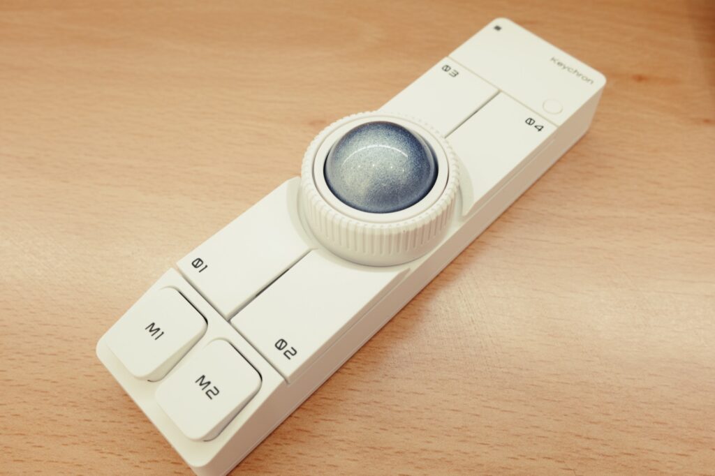 흰색 키크론 Nape Pro의 25mm 하늘색 트랙볼과 둘레의 링 형태 스크롤 휠 근접 사진  
