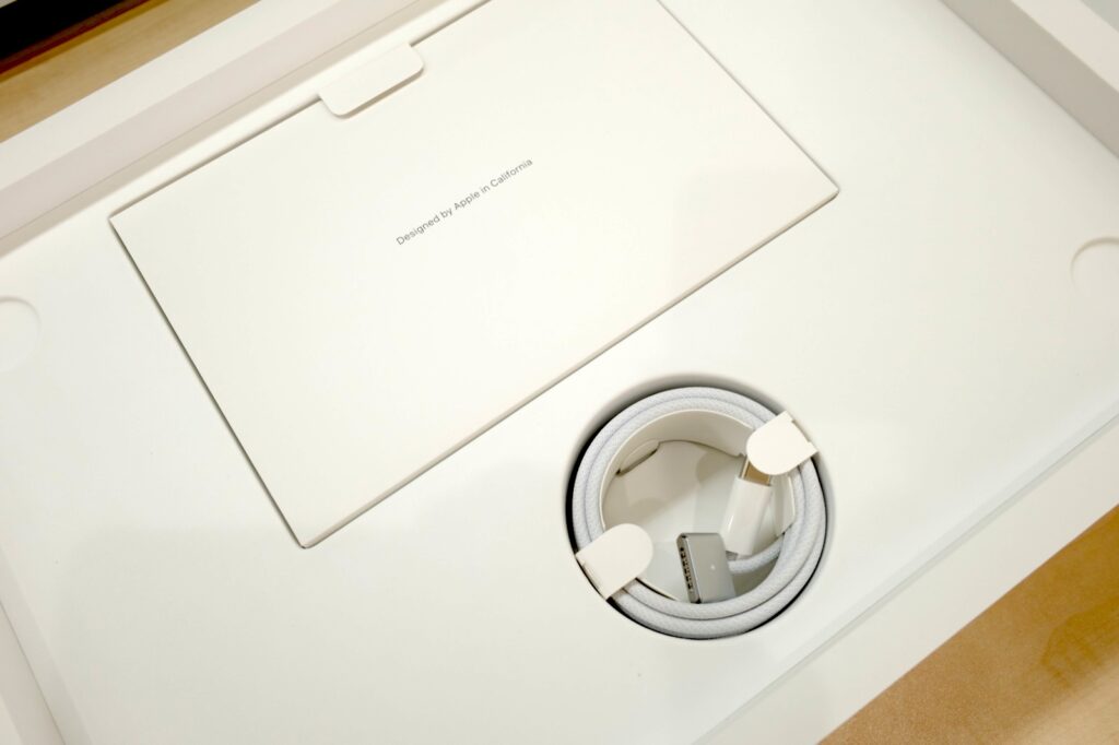 리퍼비시 맥북 프로 본체 아래 칸에 담긴 흰색 MagSafe 3 케이블과 설명서
